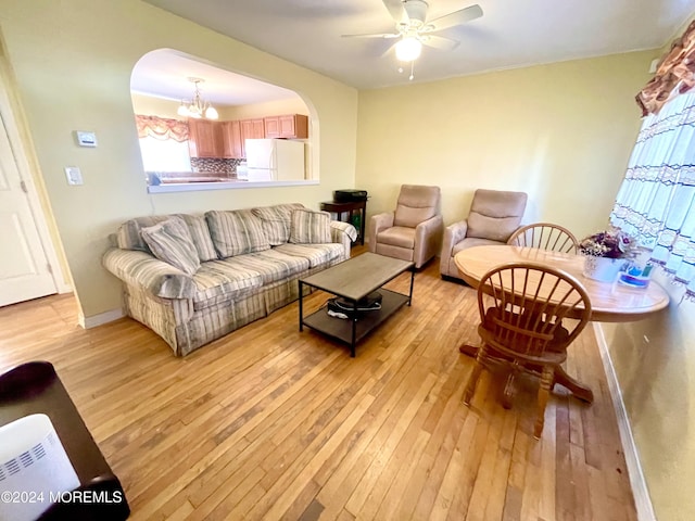 living room featuring ceiling fan with notable chandelier and light hardwood / wood-style floors