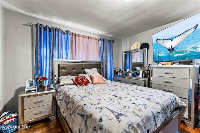 bedroom with dark hardwood / wood-style floors and a textured ceiling