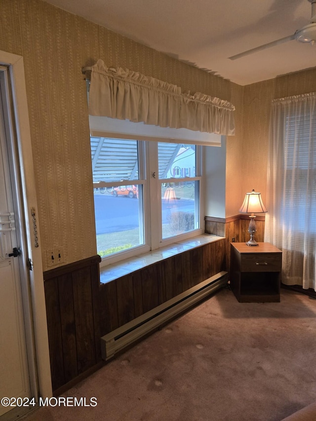 sitting room with wood walls, carpet floors, a healthy amount of sunlight, and a baseboard heating unit