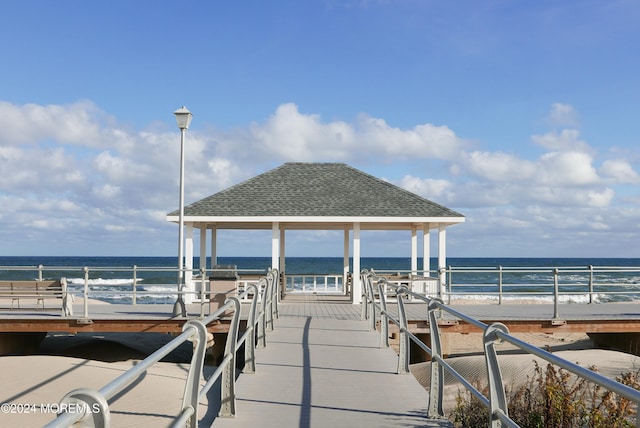 view of dock featuring a water view and a view of the beach