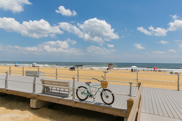 wooden deck with a water view and a beach view