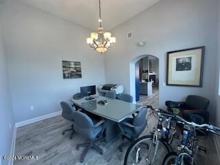 home office with hardwood / wood-style flooring, a notable chandelier, and high vaulted ceiling