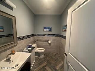 bathroom with parquet flooring, vanity, toilet, and tile walls