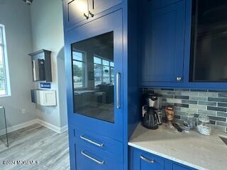 kitchen with blue cabinetry, decorative backsplash, and hardwood / wood-style floors