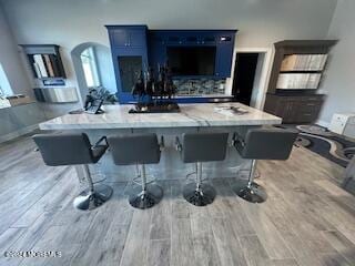 bar featuring wood-type flooring and blue cabinets