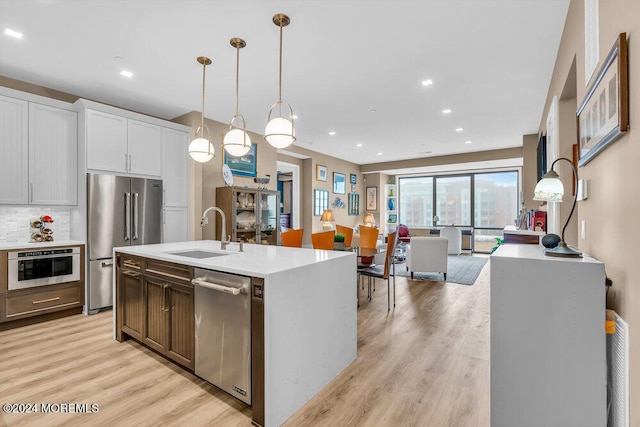 kitchen featuring pendant lighting, white cabinets, sink, an island with sink, and stainless steel appliances