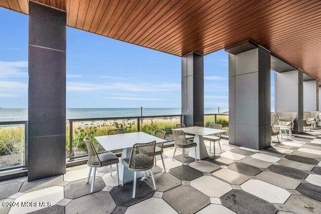 view of patio with a water view and a view of the beach