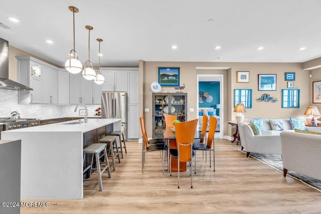 kitchen with high end refrigerator, sink, light hardwood / wood-style floors, and decorative light fixtures