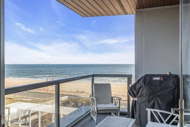 balcony featuring grilling area, a water view, and a beach view