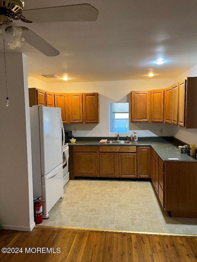 kitchen with ceiling fan, sink, stainless steel range oven, white fridge, and light wood-type flooring