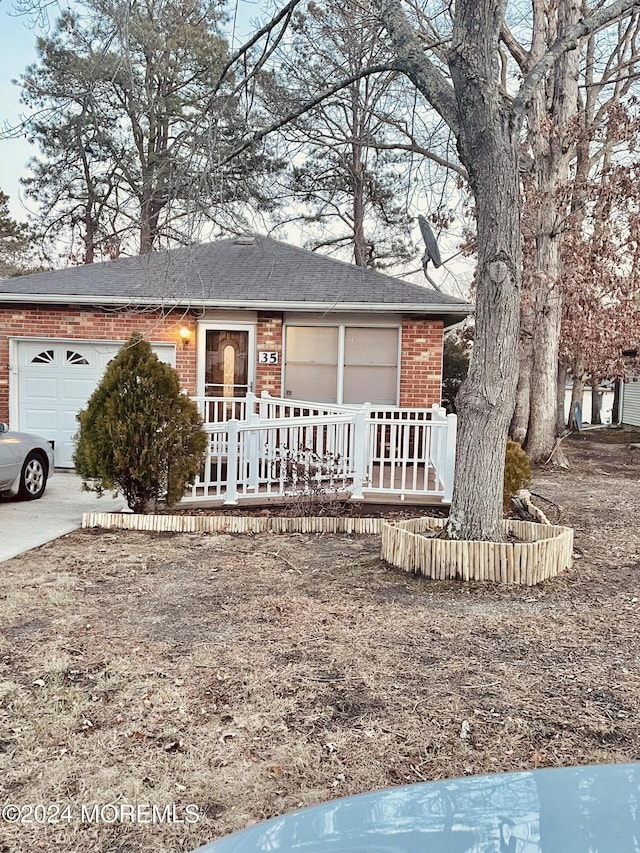 single story home featuring covered porch, brick siding, roof with shingles, and a garage