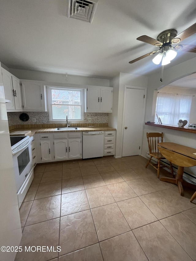 kitchen with white appliances, tasteful backsplash, light countertops, white cabinetry, and a sink