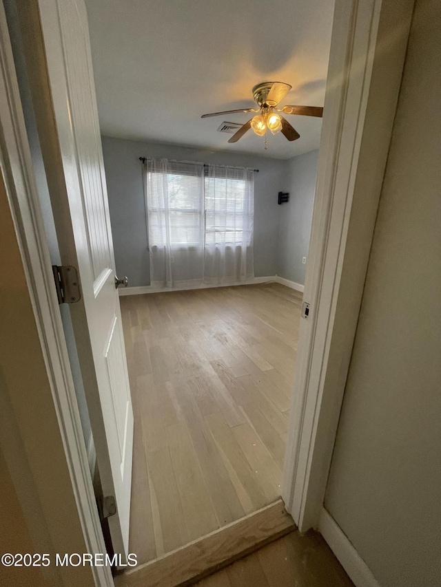 spare room with light wood-style flooring, visible vents, ceiling fan, and baseboards