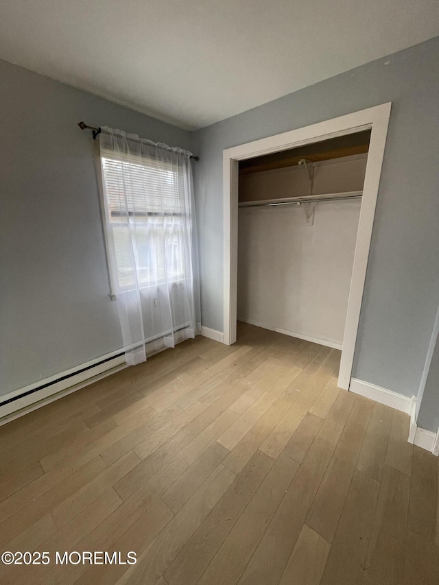 unfurnished bedroom featuring baseboards, a closet, and light wood-style floors