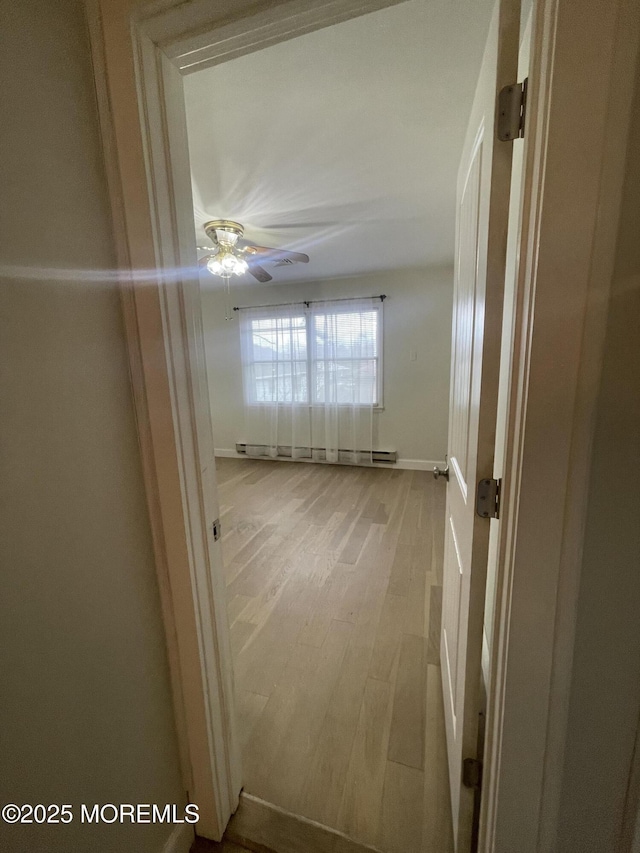 hallway with baseboards, baseboard heating, and wood finished floors