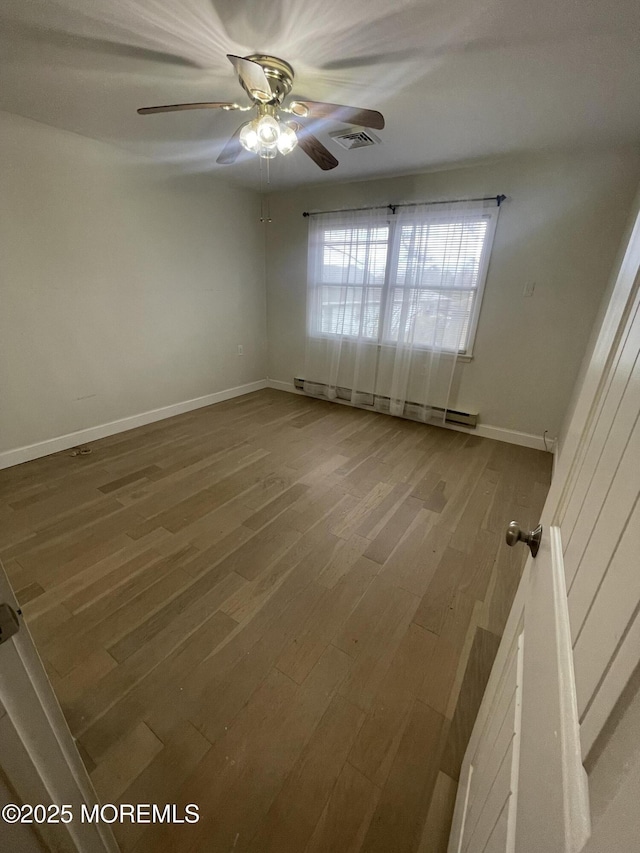 spare room featuring ceiling fan, wood finished floors, visible vents, baseboards, and baseboard heating