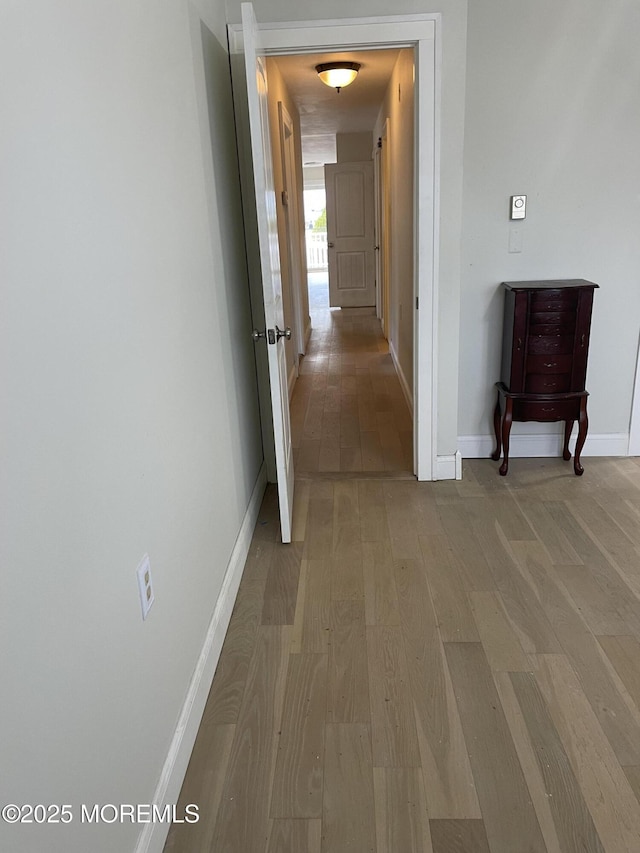 corridor featuring baseboards and light wood finished floors