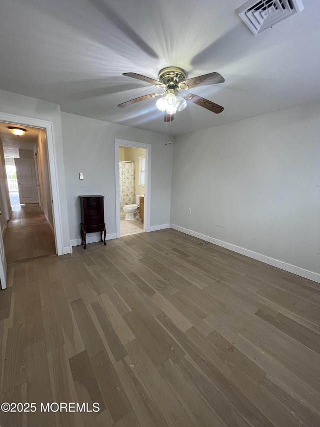 unfurnished room featuring a ceiling fan, wood finished floors, visible vents, and baseboards