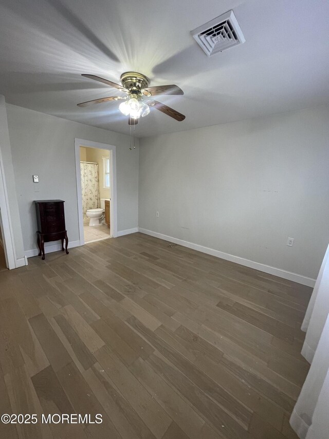 spare room featuring visible vents, ceiling fan, baseboards, and wood finished floors