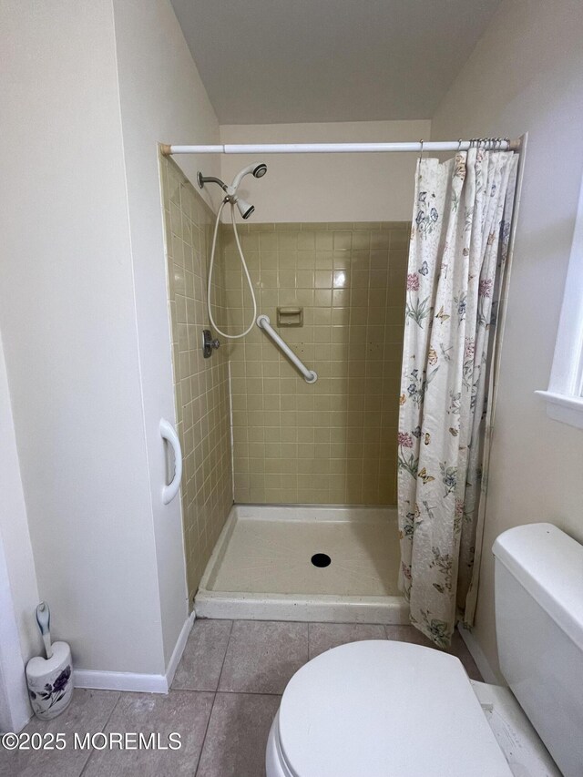 full bath featuring tile patterned flooring, baseboards, a shower stall, and toilet