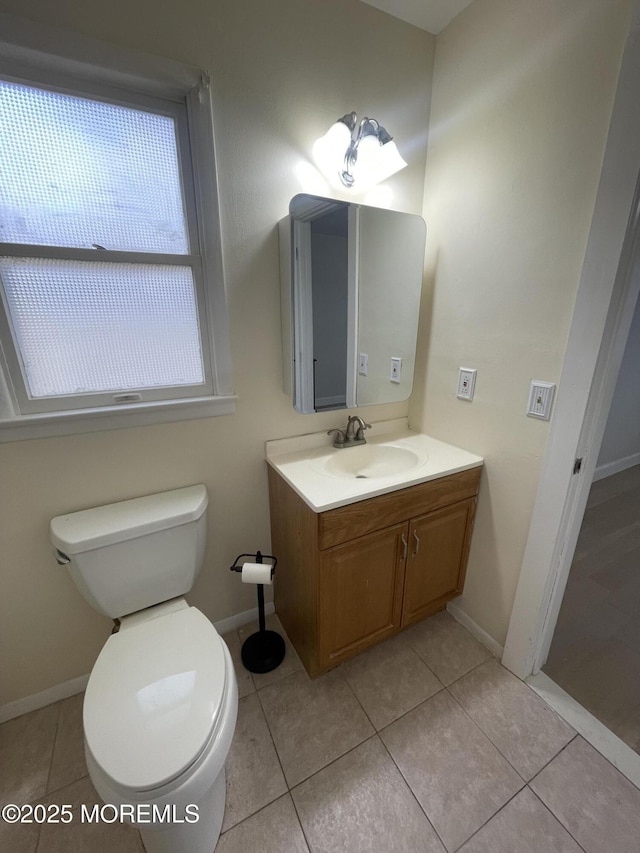 half bathroom featuring toilet, tile patterned flooring, vanity, and baseboards