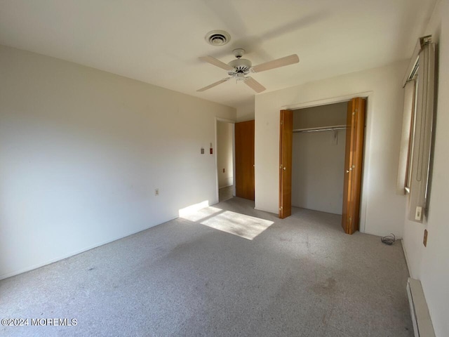 unfurnished bedroom with ceiling fan, a closet, light carpet, and a baseboard heating unit