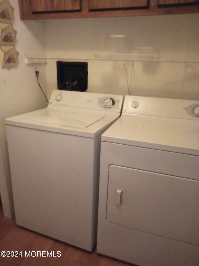 laundry room featuring cabinets, washing machine and dryer, and dark hardwood / wood-style floors