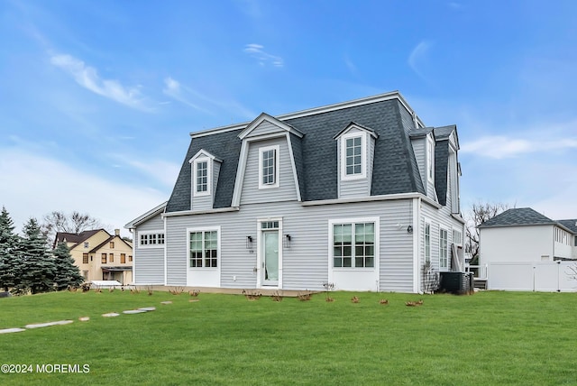 view of front facade featuring a shingled roof, a front yard, and central air condition unit