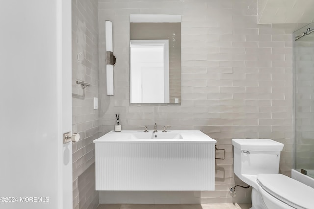 bathroom with tile walls, vanity, toilet, and walk in shower