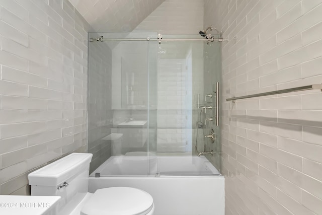 bathroom with bath / shower combo with glass door, toilet, and tile walls