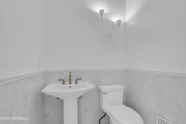 bathroom with toilet and a wainscoted wall