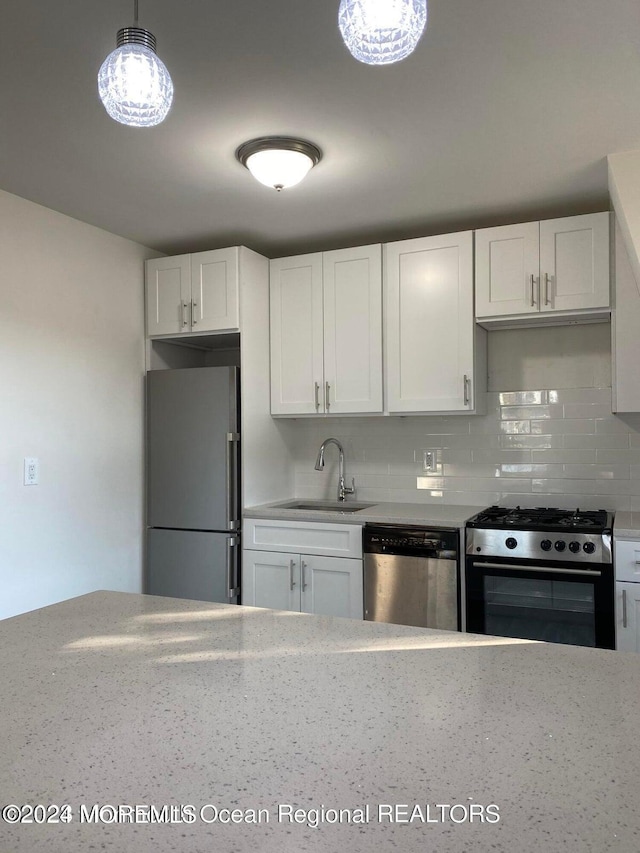 kitchen featuring appliances with stainless steel finishes, backsplash, a sink, and white cabinetry