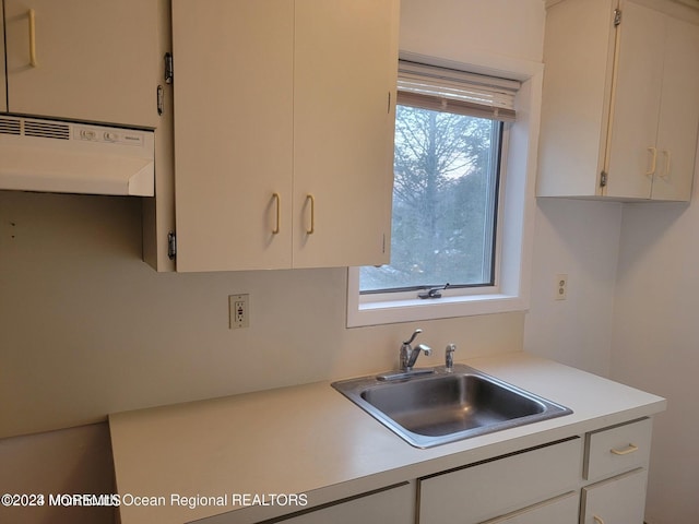 kitchen featuring white cabinetry, light countertops, a sink, and extractor fan