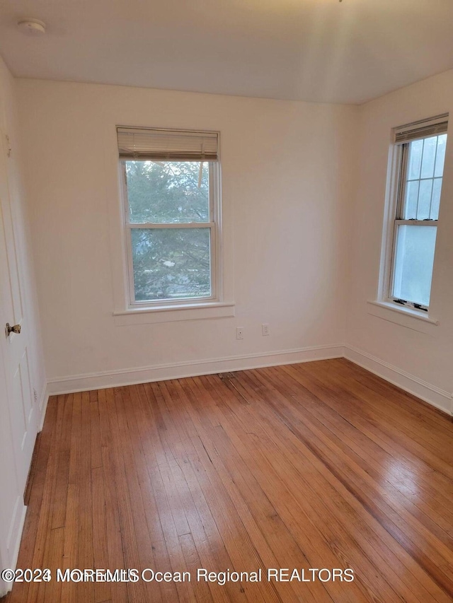 empty room with wood-type flooring and baseboards