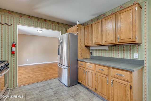 kitchen featuring stainless steel refrigerator with ice dispenser and range with gas cooktop