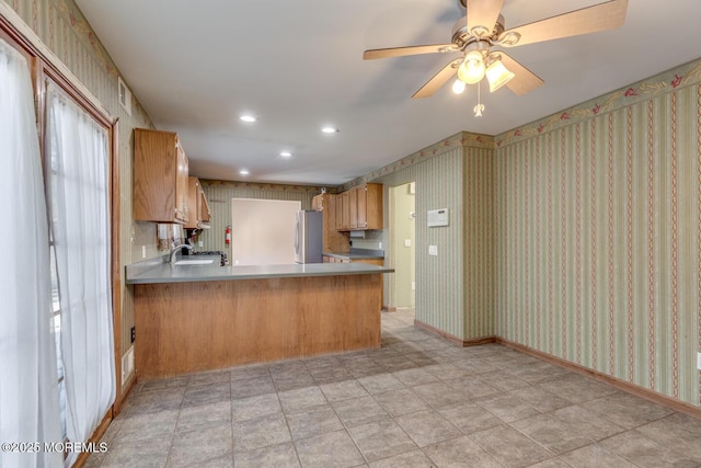 kitchen with ceiling fan, stainless steel fridge, kitchen peninsula, and sink