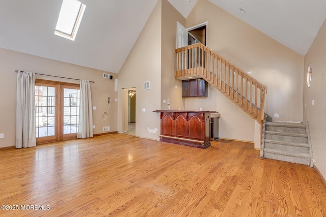 unfurnished living room featuring light wood-type flooring, high vaulted ceiling, and a skylight