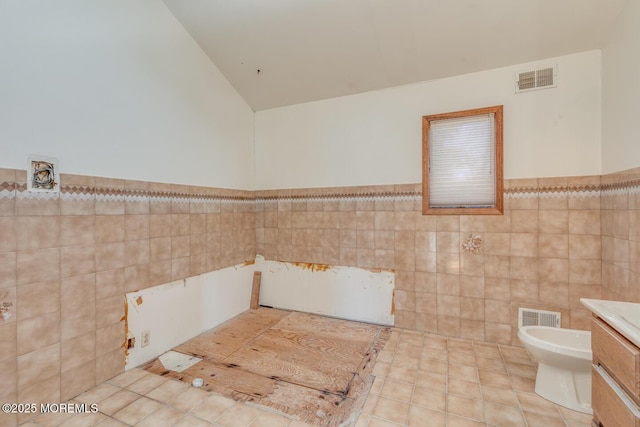 bathroom featuring tile patterned flooring, vanity, toilet, and tile walls