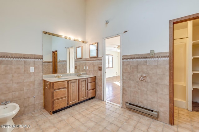 bathroom featuring a bidet, a baseboard radiator, tile patterned floors, and tile walls