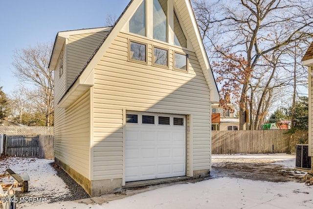 snow covered property with cooling unit and a garage