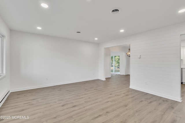 spare room featuring a baseboard heating unit and light hardwood / wood-style flooring