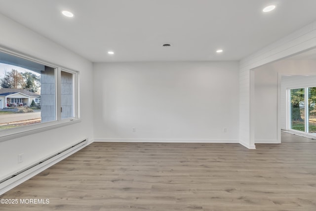 empty room with a baseboard radiator and light hardwood / wood-style floors