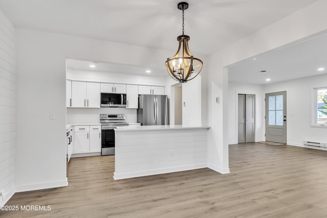 kitchen featuring stainless steel appliances, white cabinetry, pendant lighting, and light wood-type flooring