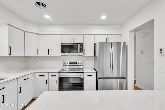 kitchen with white cabinetry, appliances with stainless steel finishes, and light stone counters