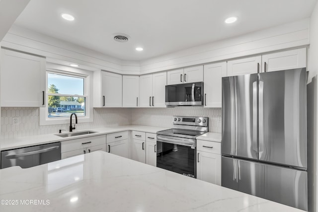 kitchen with sink, stainless steel appliances, and light stone countertops