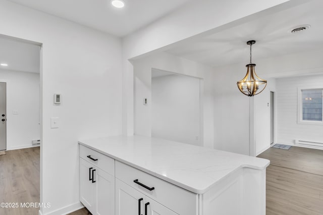 kitchen with white cabinetry, decorative light fixtures, light hardwood / wood-style floors, and light stone counters