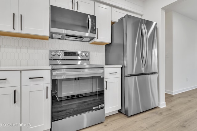 kitchen featuring stainless steel appliances, decorative backsplash, and white cabinets