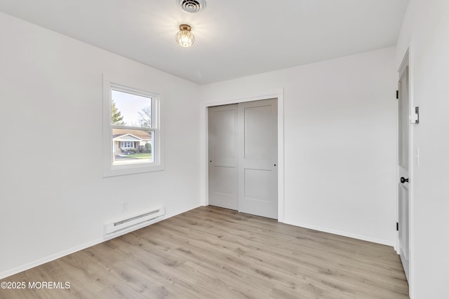 unfurnished bedroom with a baseboard radiator, a closet, and light hardwood / wood-style flooring