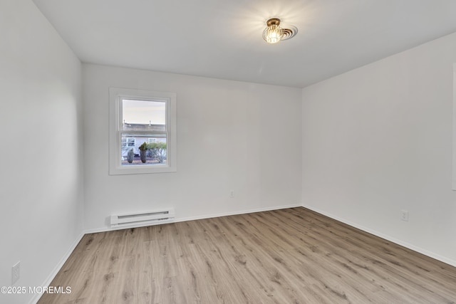 unfurnished room with a baseboard heating unit and light hardwood / wood-style flooring