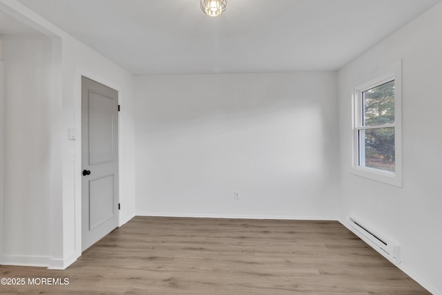 unfurnished room featuring a baseboard radiator and light wood-type flooring